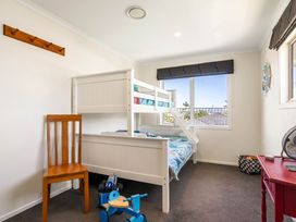 A bedroom with a bunk bed and chair at Ohana - Papamoa Holiday Home in Papamoa