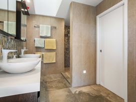 A bathroom with double sinks and towels hanging at Ohana - Papamoa Holiday Home in Papamoa
