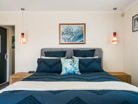 A bedroom with a bed and bedside lamps at Ohana - Papamoa Holiday Home in Papamoa