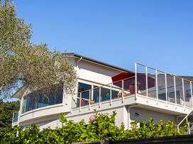 A house with a balcony and umbrella at Ohana - Papamoa Holiday Home Papamoa