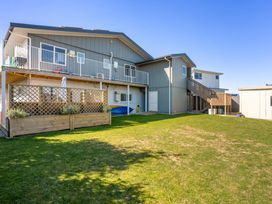 A house with a balcony and lawn at Ohana - Papamoa Holiday Home, Papamoa