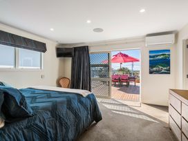 A bedroom with a bed and view of outdoor area at Ohana - Papamoa Holiday Home Papamoa