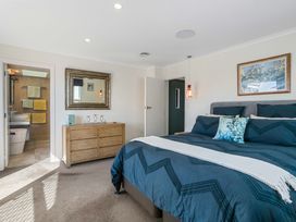 A bedroom with a bed and bathroom access at Ohana - Papamoa Holiday Home, Papamoa