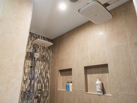 A shower area with dual shower heads and products on shelves at Ohana - Papamoa Holiday Home Papamoa
