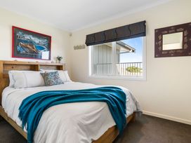 A bedroom with a bed and a window at Ohana - Papamoa Holiday Home 