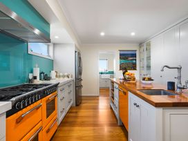 A kitchen with a cooking range and refrigerator at Ohana - Papamoa Holiday Home