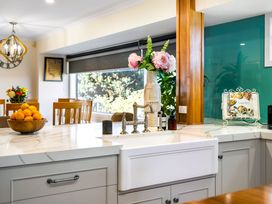 A kitchen with a sink, fruit bowl, and flowers at Ohana - Papamoa Holiday Home