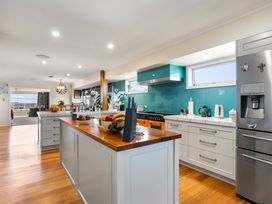 A kitchen with a stove and refrigerator at Ohana - Papamoa Holiday Home