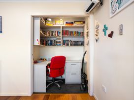 A home office with a desk and bookshelf at Ohana - Papamoa Holiday Home