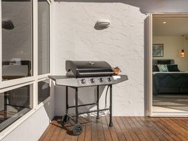 An outdoor area with a grill on a wooden deck at Ohana - Papamoa Holiday Home