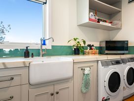 A laundry room with a sink and washing machines at Ohana - Papamoa Holiday Home
