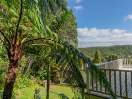 A deck with palm trees and a view of the forest at Skipper’s view - Onemana Holiday Home in Onemana