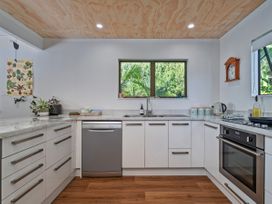 A kitchen with cabinets and a sink near a window at Skipper’s view - Onemana Holiday Home, Onemana