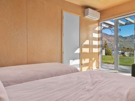 A bedroom with two beds and a door leading to outside at Peak Perspective - Wanaka Holiday Home