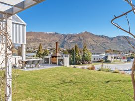 An outdoor dining area with chairs and a wood-fired oven at Peak Perspective - Wanaka Holiday Home in Wanaka