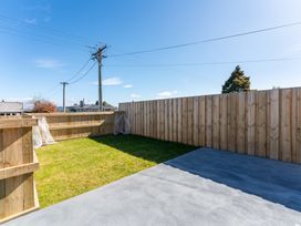 A garden area with grass and a concrete patio at The Cozy Koha - Taupo Holiday Home, Taupo