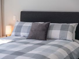A bedroom with a bed and lamp at The Cozy Koha - Taupo Holiday Home