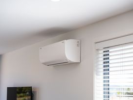 A living room with an air conditioner and window blinds at The Cozy Koha - Taupo Holiday Home, Taupo