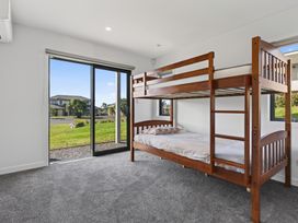 A bedroom with a bunk bed and large windows at Starling - Mangawhai Heads Holiday Home in Mangawhai Heads