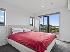 A bedroom with a bed and windows at Starling - Mangawhai Heads Holiday Home Mangawhai Heads