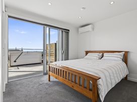 A bedroom with a bed and sliding doors at Starling - Mangawhai Heads Holiday Home Mangawhai Heads