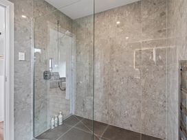 A shower with glass wall and tiled surface at Starling - Mangawhai Heads Holiday Home Mangawhai Heads