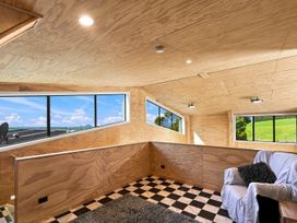 A living room with a sofa and large windows at The Black Barn - Whakatane Holiday Home Whakatane