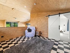 A snug area with an armchair and sliding door at The Black Barn - Whakatane Holiday Home in Whakatane