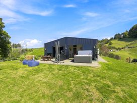 An outdoor area with a house and hot tub at The Black Barn - Whakatane Holiday Home Whakatane