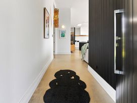 A hallway with wall art and a rug at The Black Barn - Whakatane Holiday Home in Whakatane
