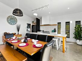A dining room with a table set for meals at The Black Barn - Whakatane Holiday Home in Whakatane