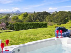 A hot tub with glasses on the edge and a landscape view at The Black Barn - Whakatane