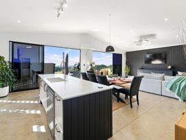 A living room with a kitchen island and dining table at The Black Barn - Whakatane Holiday Home in Whakatane