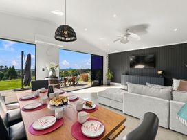 A living room with a table set for dining and a tv at The Black Barn - Whakatane Holiday Home in Whakatane