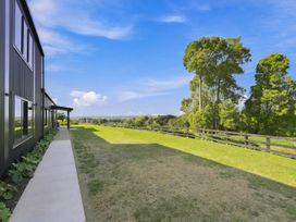 An outdoor area with a building, pathway, grass, trees, and a fence at The Black Barn - Whakatane Holiday Home Whakatane