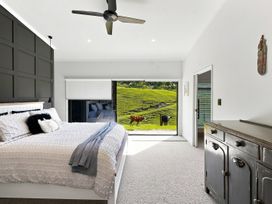 A bedroom with a bed and a view of cows outside at The Black Barn - Whakatane Holiday Home Whakatane