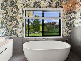A bathroom with a bathtub and window view at The Black Barn - Whakatane Holiday Home, Whakatane