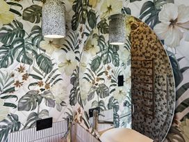 A bathroom with a mirror and floral wallpaper at The Black Barn - Whakatane Holiday Home in Whakatane