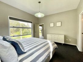 A bedroom with a bed and window at Vinnie’s haven - Opunake Holiday Home