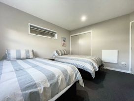 A bedroom with two beds and a cupboard at Vinnie’s haven - Opunake Holiday Home