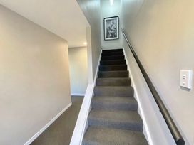 A staircase with a handrail in a hallway at Vinnie’s haven - Opunake Holiday Home