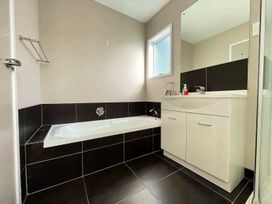 A bathroom with a bathtub and vanity at Vinnie’s haven - Opunake Holiday Home