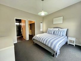 A bedroom with a bed and wardrobe at Vinnie’s haven - Opunake Holiday Home