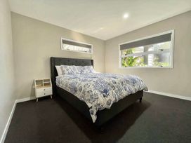 A bedroom with a bed and nightstand at Vinnie’s haven - Opunake Holiday Home