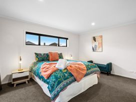 A bedroom with a bed and armchair at Hosking Haven - Cromwell Holiday Home