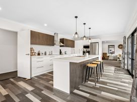 A kitchen with bar stools and appliances at Hosking Haven - Cromwell Holiday Home, Cromwell