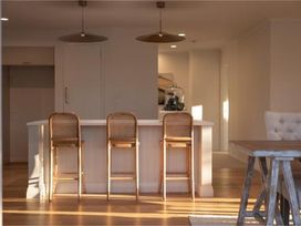 A kitchen with bar stools and light fixtures at Poolside on Moffat - Tauranga