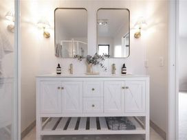 A bathroom with a double vanity and mirrors at Poolside on Moffat - Tauranga