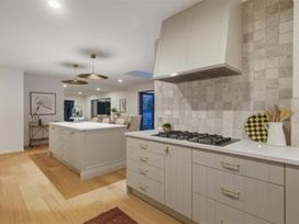 A kitchen with a stove and cabinets at Poolside on Moffat - Tauranga