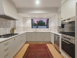 A kitchen with cabinets and appliances at Poolside on Moffat - Tauranga